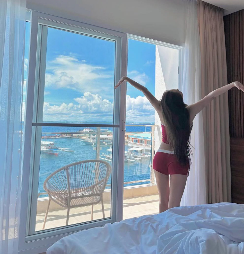 Minyoung shows off her toned body in red shorts against a stunning ocean backdrop
