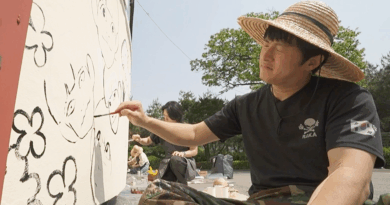 I Live Alone member paints mural with junior artists in a colorful volunteer event