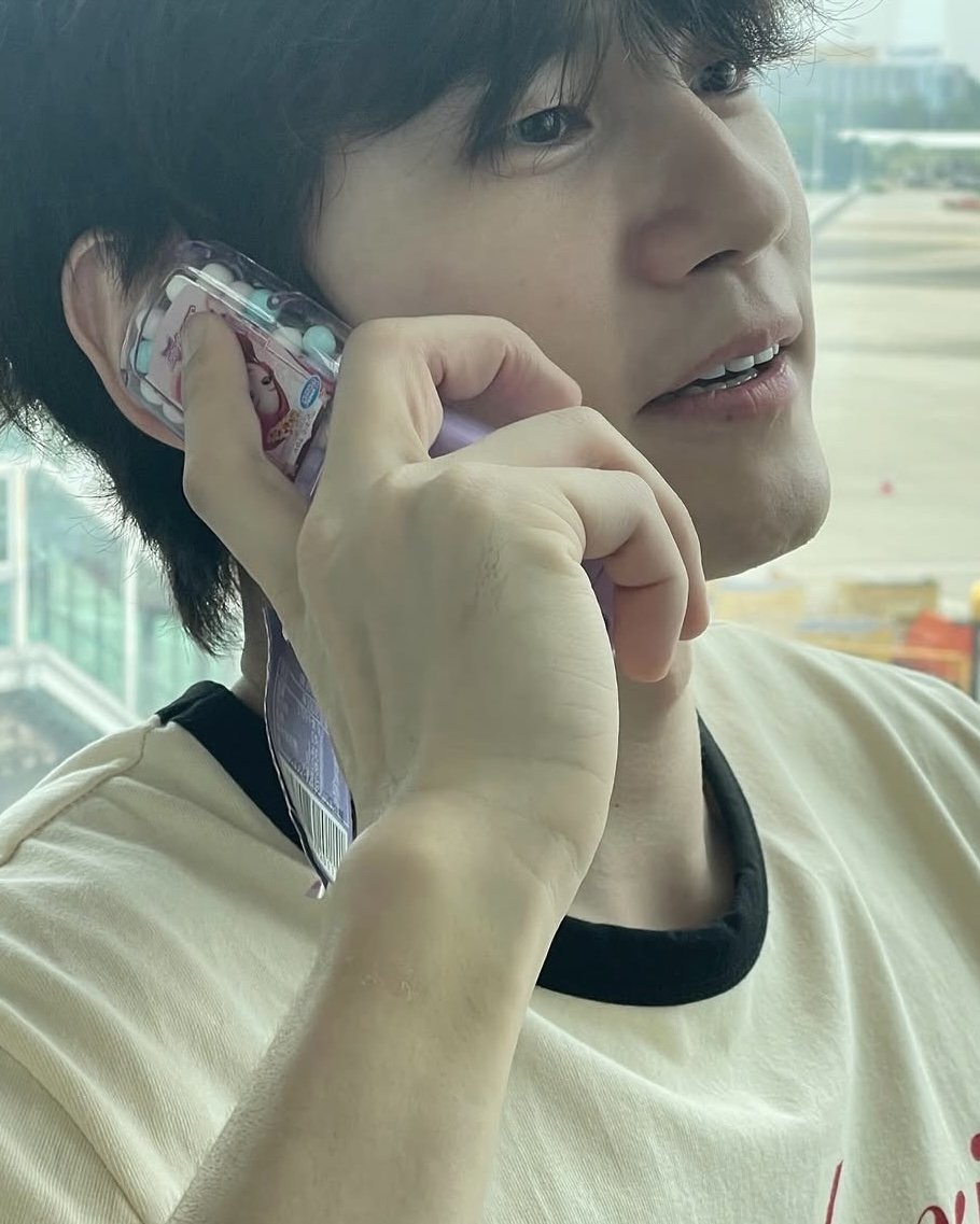 Actor Ong Seong-wu at the airport with fans bidding farewell and holding a toy phone